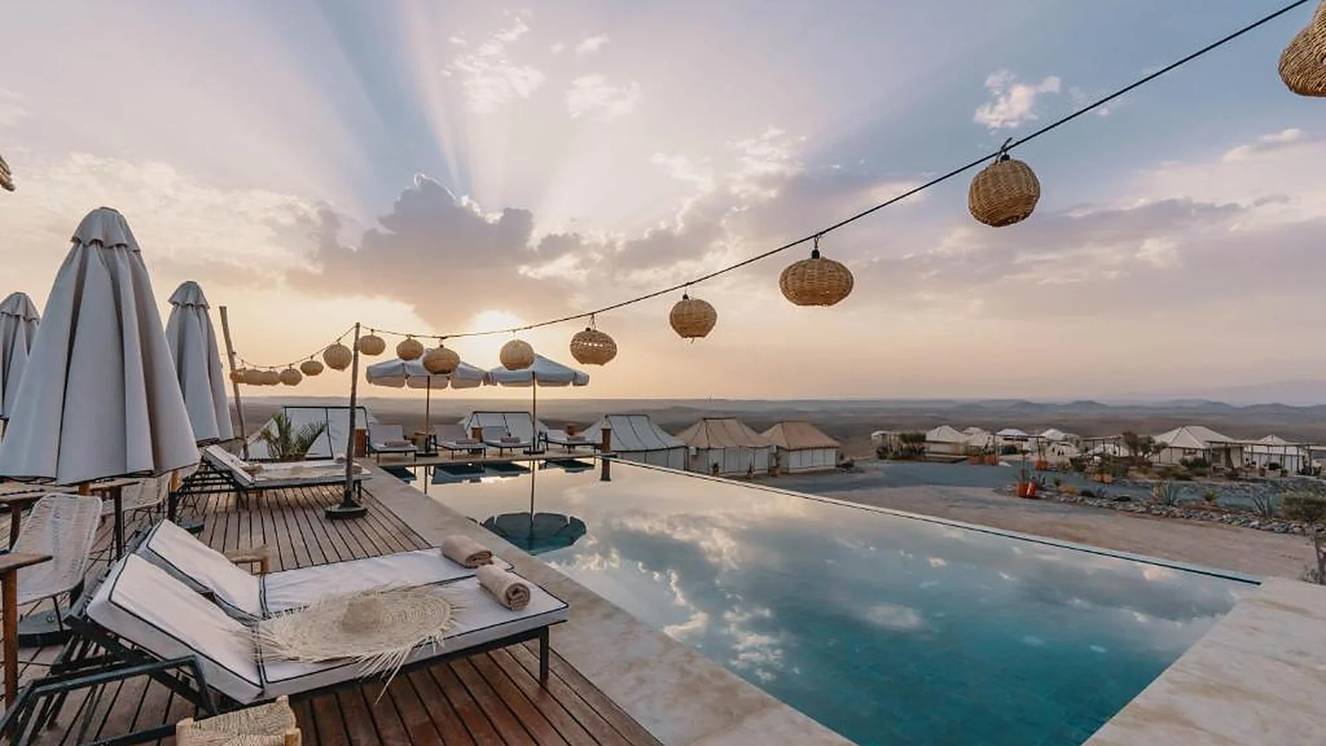 Piscine à débordement et lanternes au coucher du soleil, camp du désert d’Agafay